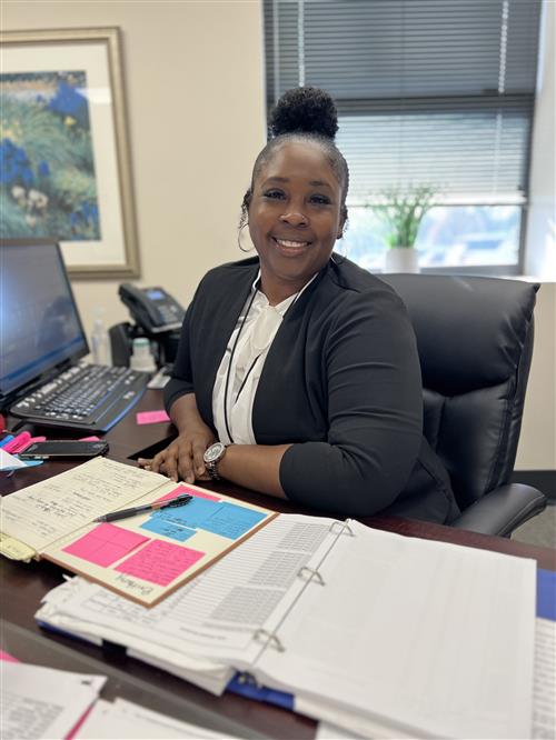 Brittany smiles to camera while sitting at her desk.